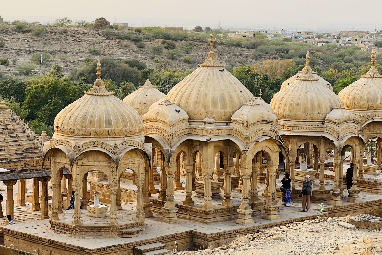 Cenotáfios de arenito de Bada Bagh, em Jaisalmer, com visitantes entre as colunas ao fim da tarde